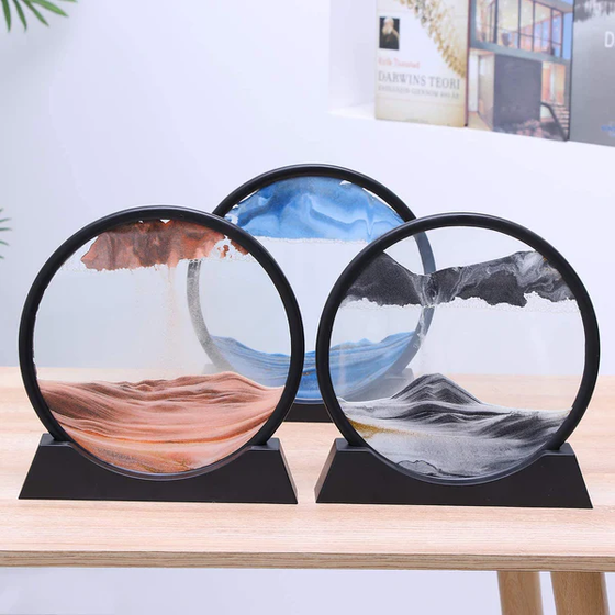 Three decorative 3D sand art pictures in circular frames with colorful sand patterns on stands