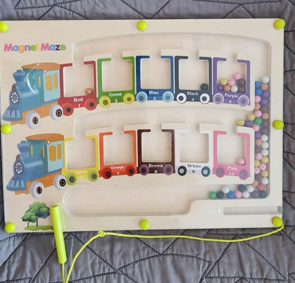 Colorful Montessori puzzle game board featuring a magnetic maze with a train theme and colorful beads