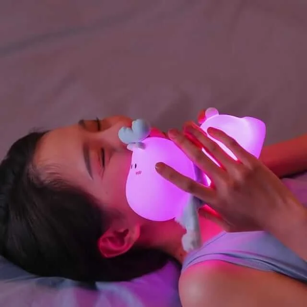 Kawaii reindeer touch lamp for kids glowing softly in a child's hands while relaxing in bed
