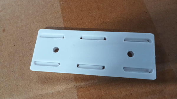 White self adhesive power strip holder with mounting holes on a brown surface