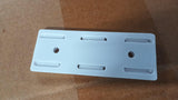 White self adhesive power strip holder with mounting holes on a brown surface