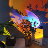 Sunset projection lamp 16 colors casting vibrant shadows on a vase with flowers and a calendar